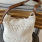 Off-white cotton woven bag showing brown leather buckle strap