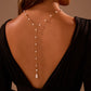 Model back view showing the faux pearl backdrop necklace falling from the nape to a teardrop pearl