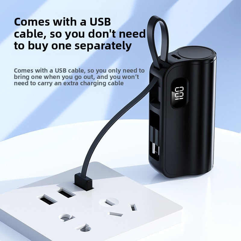 Black capsule power bank with a lanyard cable plugged into a wall socket, display showing the battery level