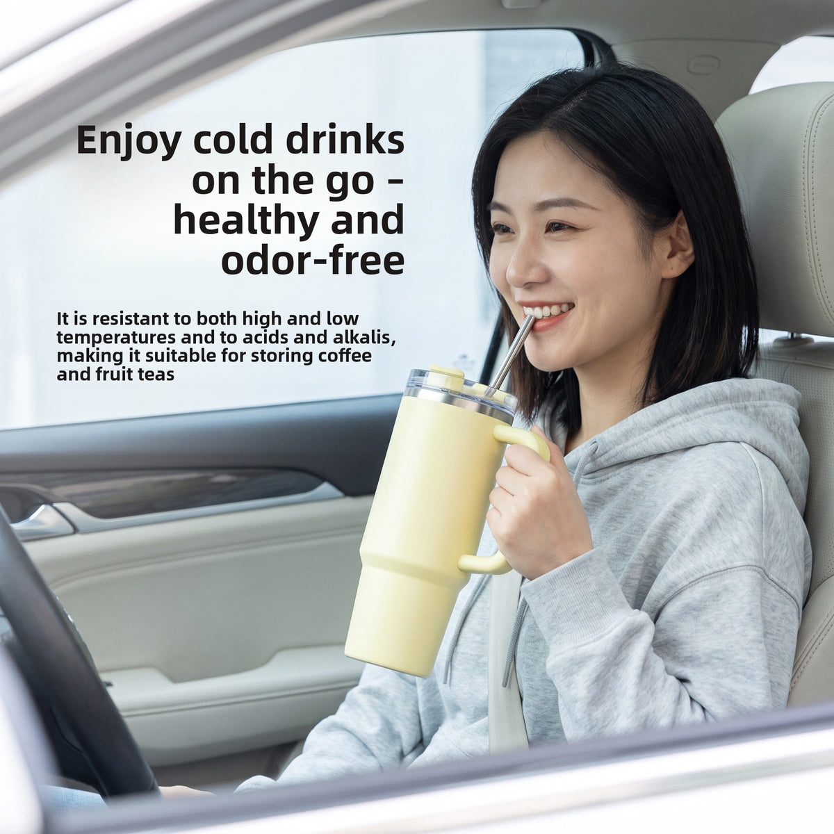 Woman drinking through a titanium straw from a yellow handled tumbler while seated in a car