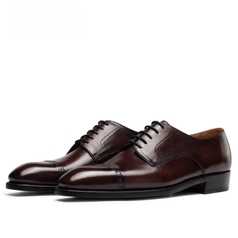 Brown burnished cowhide derby shoes seen from the front, squared cap toe and five eyelet open lacing