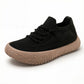 Black knit mesh slip-on sneaker with flat criss-cross laces and a thick tan crackle-pattern sole on white