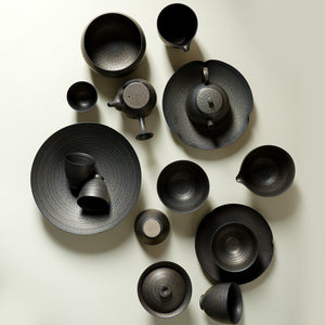 Overhead view of iron glaze gongfu teaware with teapots gaiwan cups and pitchers arranged