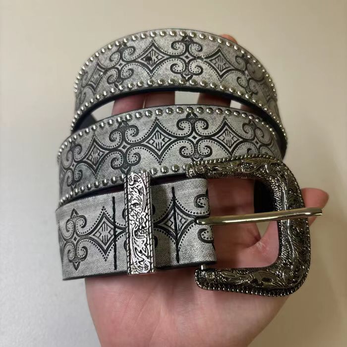 Ornate antique silver pin buckle and scrolled keeper on the grey studded western belt