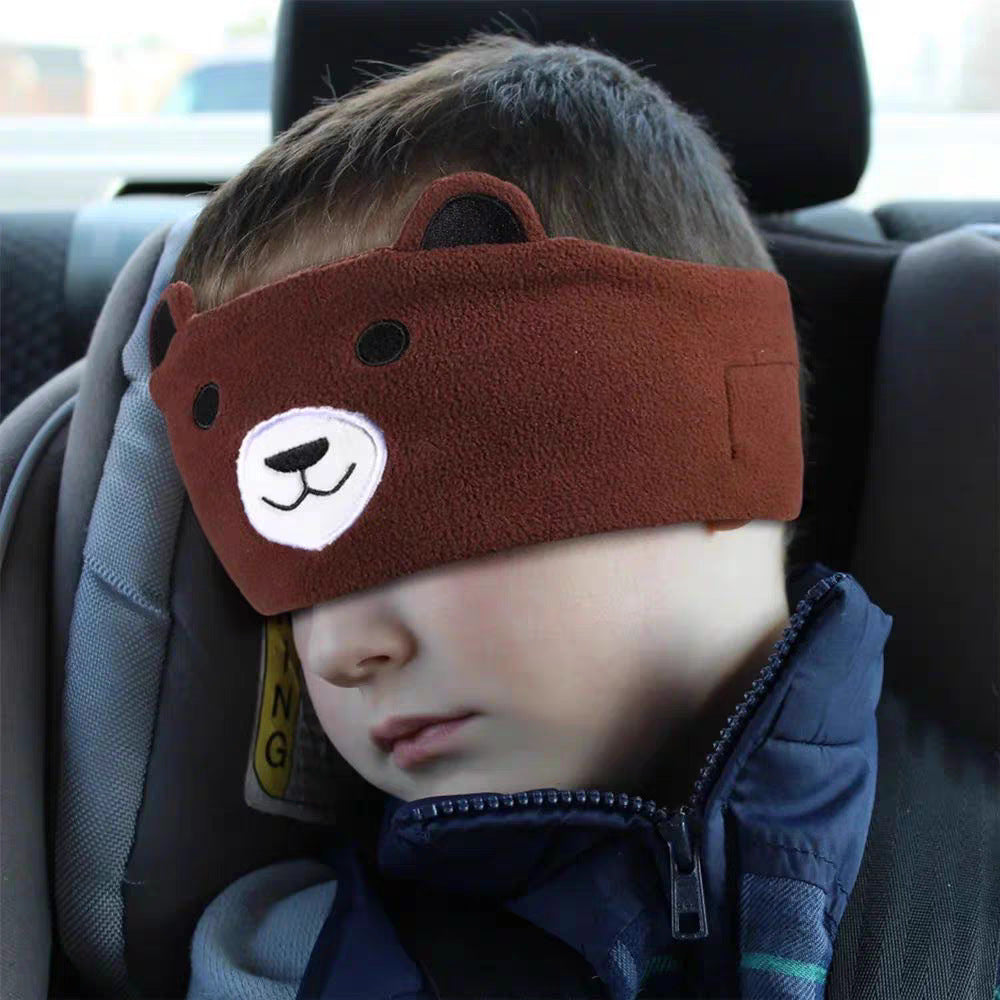 Child asleep in car seat wearing brown bear cartoon Bluetooth sleep headband over the eyes