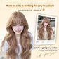 Caramel toned long wavy wig with a soft fringe worn with a white tee, waves falling past the chest