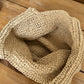 Top view into the bare crochet interior of the straw bag on a wooden table, unlined and open