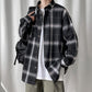 Man in black plaid oversized shirt with backpack, worn over a white tee