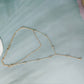 Gold tone layered Y drop rhinestone necklace laid flat on a pale green surface