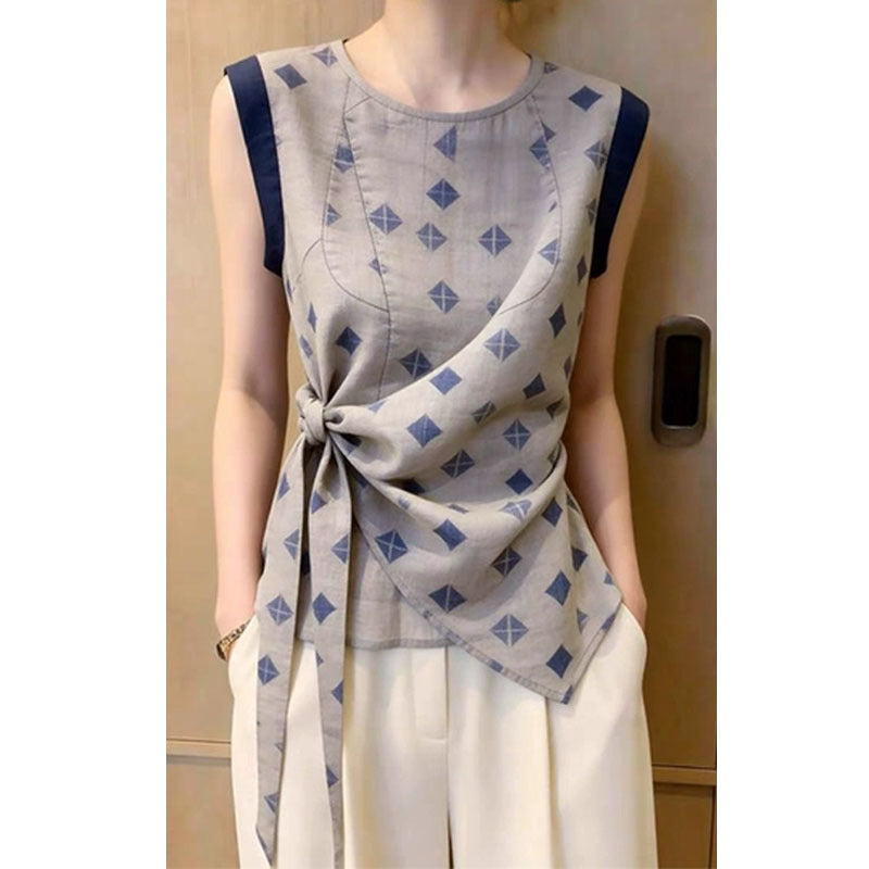 Woman wearing round neck sleeveless blouse with navy shoulder panels and waist knot