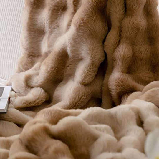 Soft ruched throw blanket in a neutral shade with a plush pile catching the light
