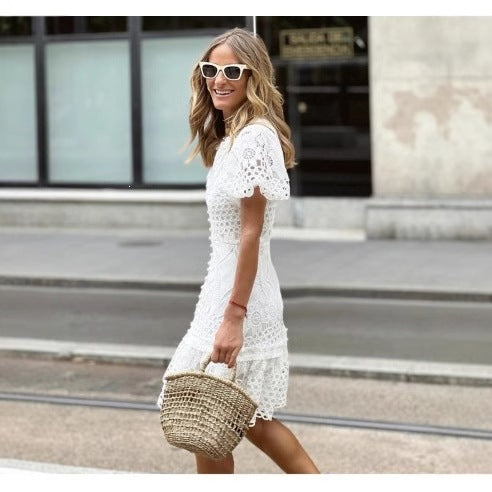 Side view of white eyelet lace short dress worn with straw bag on the street