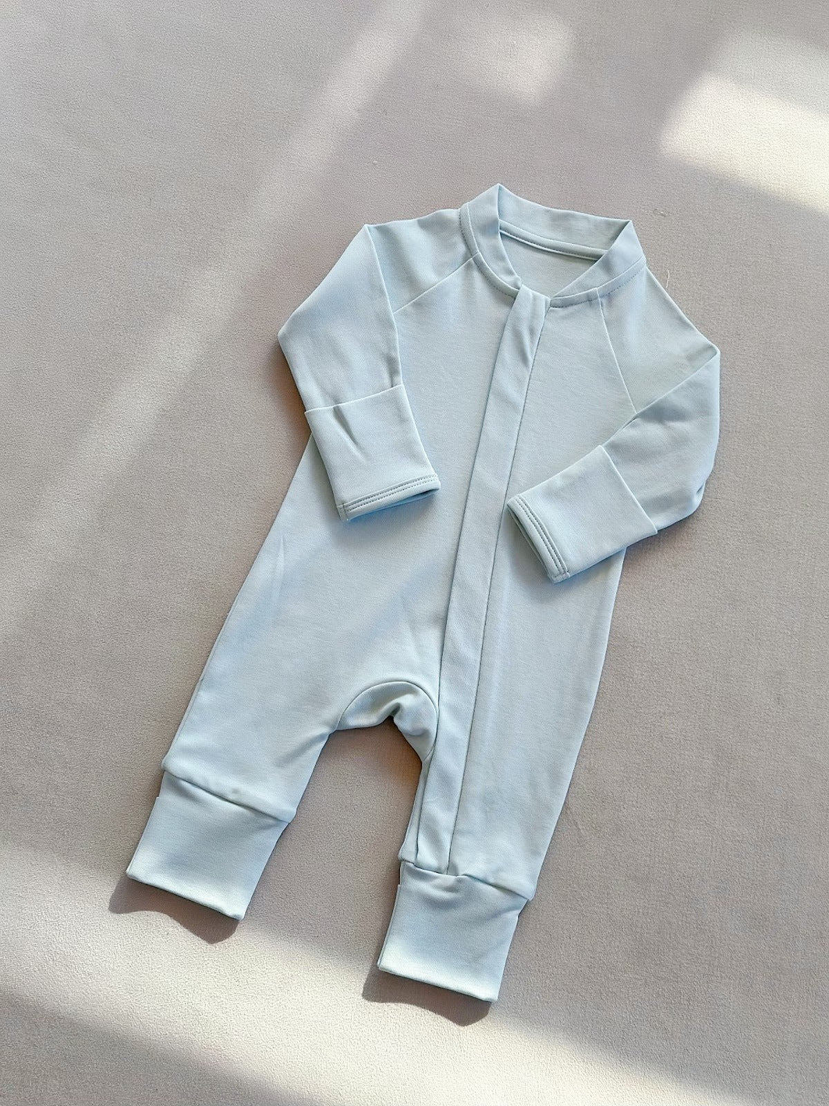 Baby Blue zip front baby romper laid flat on a gray floor, image of the 66 cm, 3 to 6 months size option