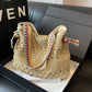 Beige open weave straw tote with colorful woven strap resting in a gift box