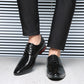 Man wearing black crocodile embossed derby shoes with black suit trousers on a light floor
