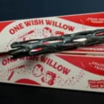 Dark knotted willow style wand laid across its printed red and white retail box