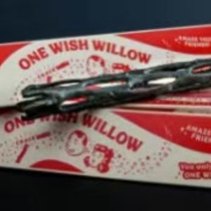 Dark knotted willow style wand laid across its printed red and white retail box