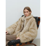 Pale blonde long pile faux fur coat worn seated, stand collar rolled up round the neck
