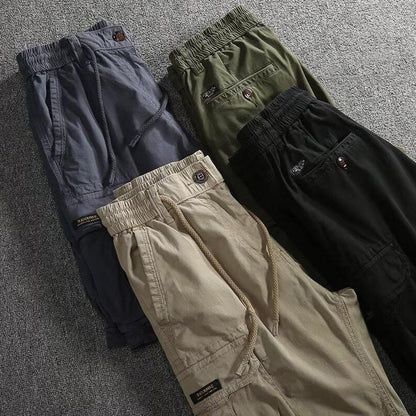 Four pairs of men's cargo shorts laid flat in khaki, black, gray and green with drawstring waists