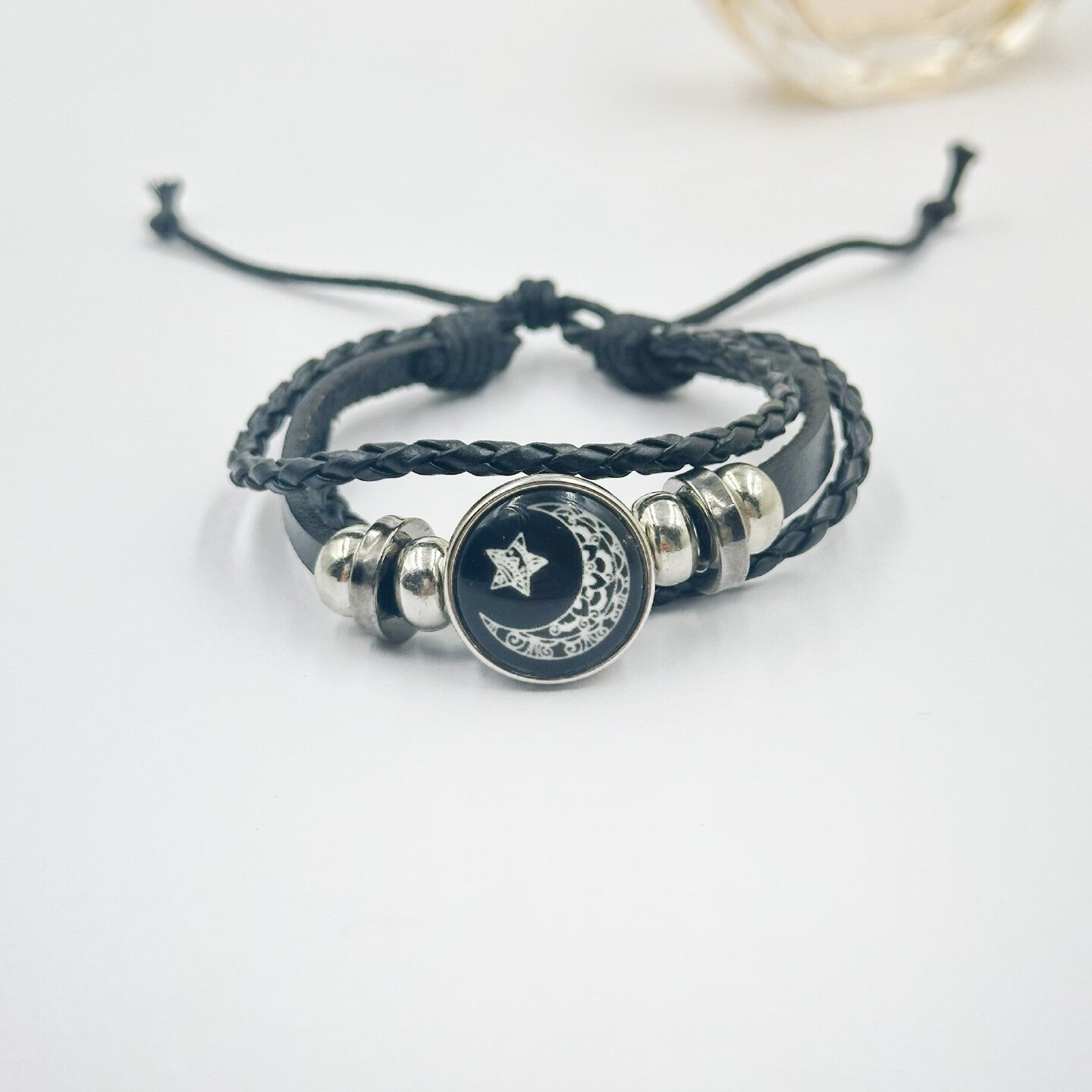 Black braided cord bracelet with a moon charm between two silver tone beads