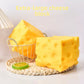 Two large cheese block squishy toys on a woven tray beside a wire basket and a lime slice
