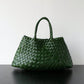 Dark green woven handbag with braided handles standing on a dark surface, Dark green variant