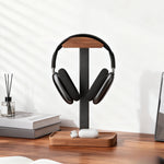 Wood headphone stand with walnut top and tray base holding a black over ear headset on a desk
