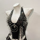 Side angle of studded punk vest showing spiked panels, skull charms and cross chains