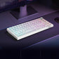White mechanical keyboard with topographic contour keycaps and RGB glow on a desk in front of a monitor