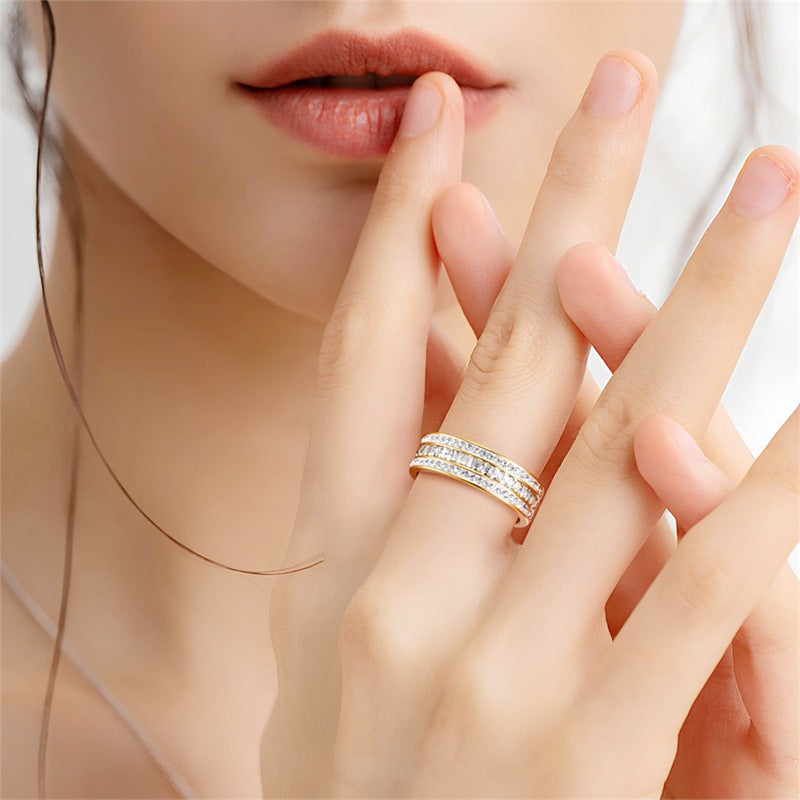 Hand held near the lips wearing a band ring with three rows of clear stones on the middle finger