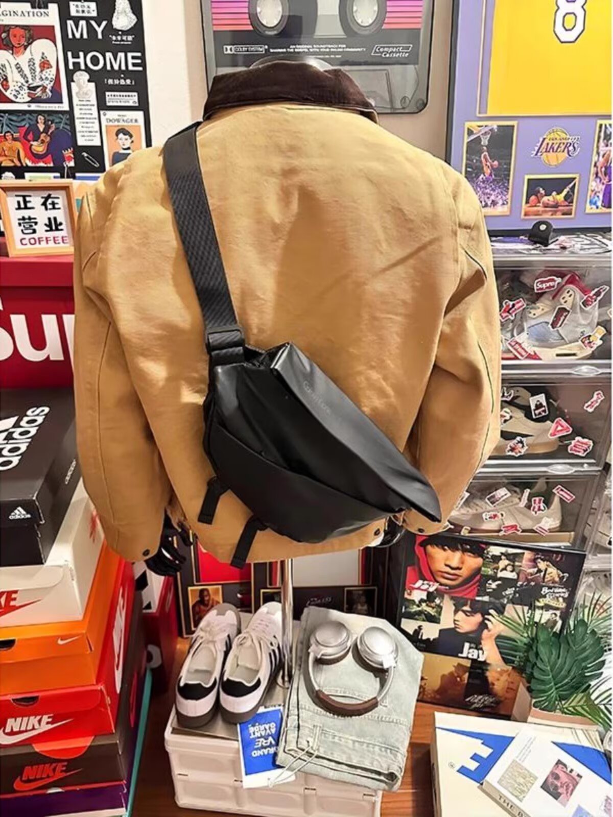 Back of the khaki zip-up jacket with brown collar and a black crossbody bag worn across the shoulder