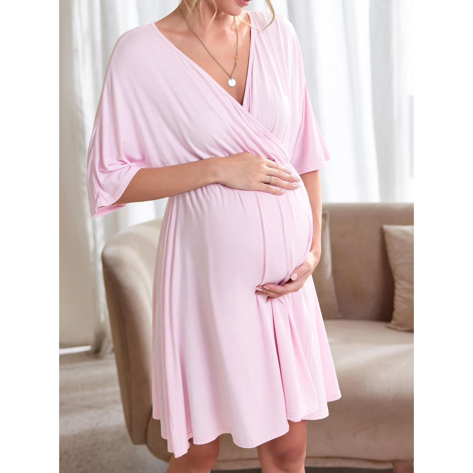 Pregnant model in a pastel maternity wrap dress standing in a sunlit living room