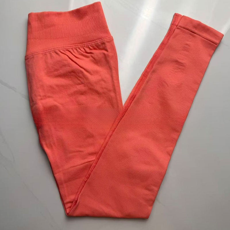 Coral pink seamless yoga leggings folded flat, showing the tall ribbed waistband
