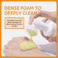Hand pressing the white pump so pale yellow foam flows through the soft silicone brush dome