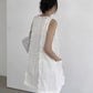 White sleeveless ruffle trim A-line mini dress shown from the back with shoulder bag