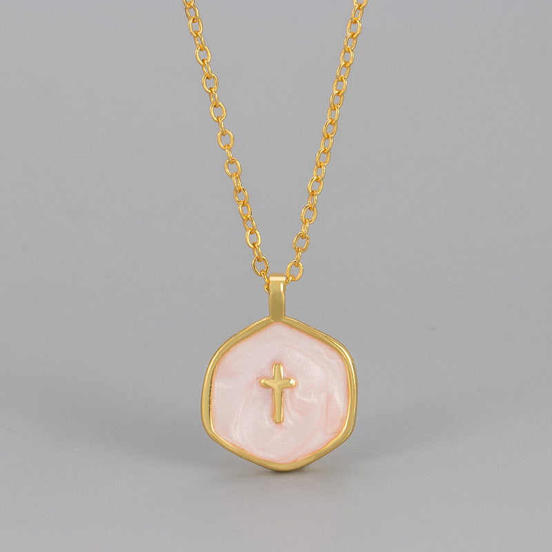 Blush pink marbled enamel cross pendant hanging from a gold tone cable chain, close view of the raised gold cross
