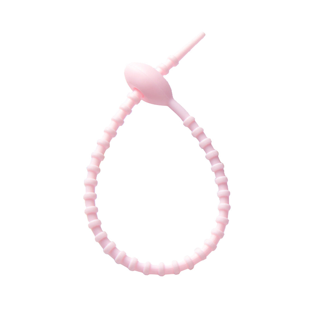 Soft silicone tadpole cable tie coiled into a loop to show the reusable cinch closure