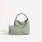 Sage green woven PU leather bucket bag with plaited handle beside its matching green zip pouch