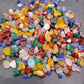 Hand holding a scoop of colourful polished agate pebbles for scale