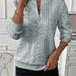 Detail of the short front zip and ring pull on a cable knit mock neck pullover