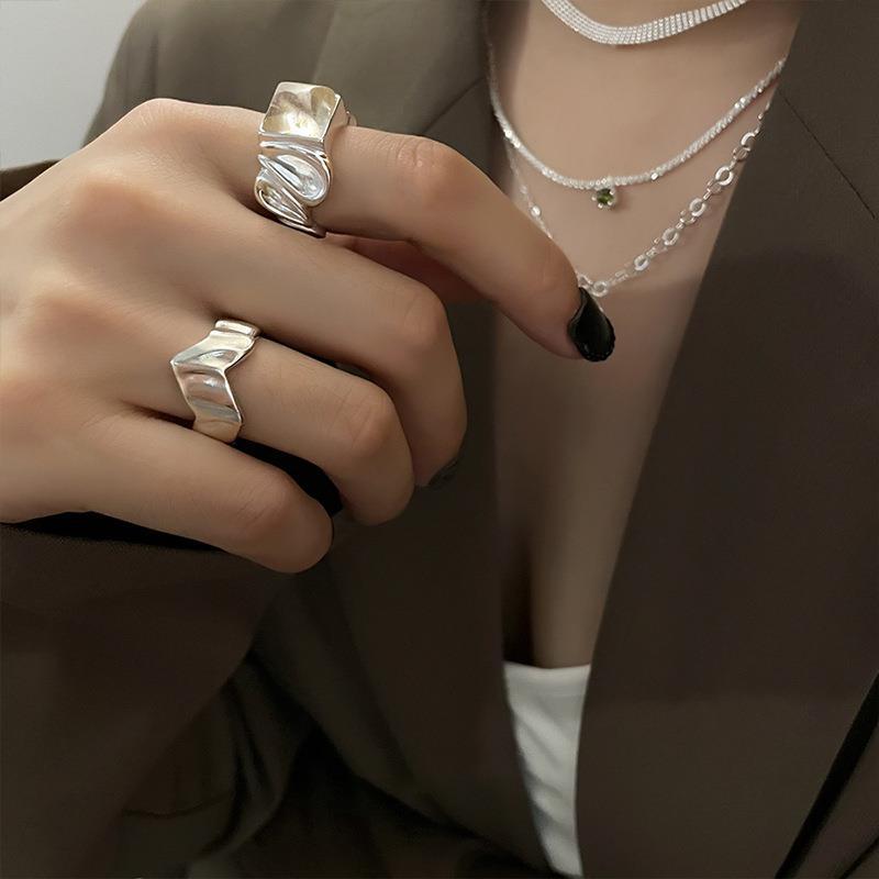 Adjustable silver ring styled on the hand next to other stacked rings