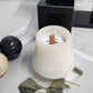 White jade marble candle cup with a flat wooden wick beside black and cream stone burner spheres