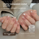 Glossy nude manicured nails beside a small clear jar of transparent crystal nail powder