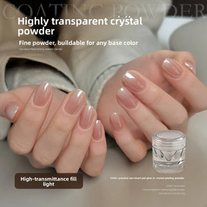 Glossy nude manicured nails beside a small clear jar of transparent crystal nail powder