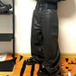 Black coated denim jeans on the body, wide relaxed leg breaking long over chunky black boots indoors