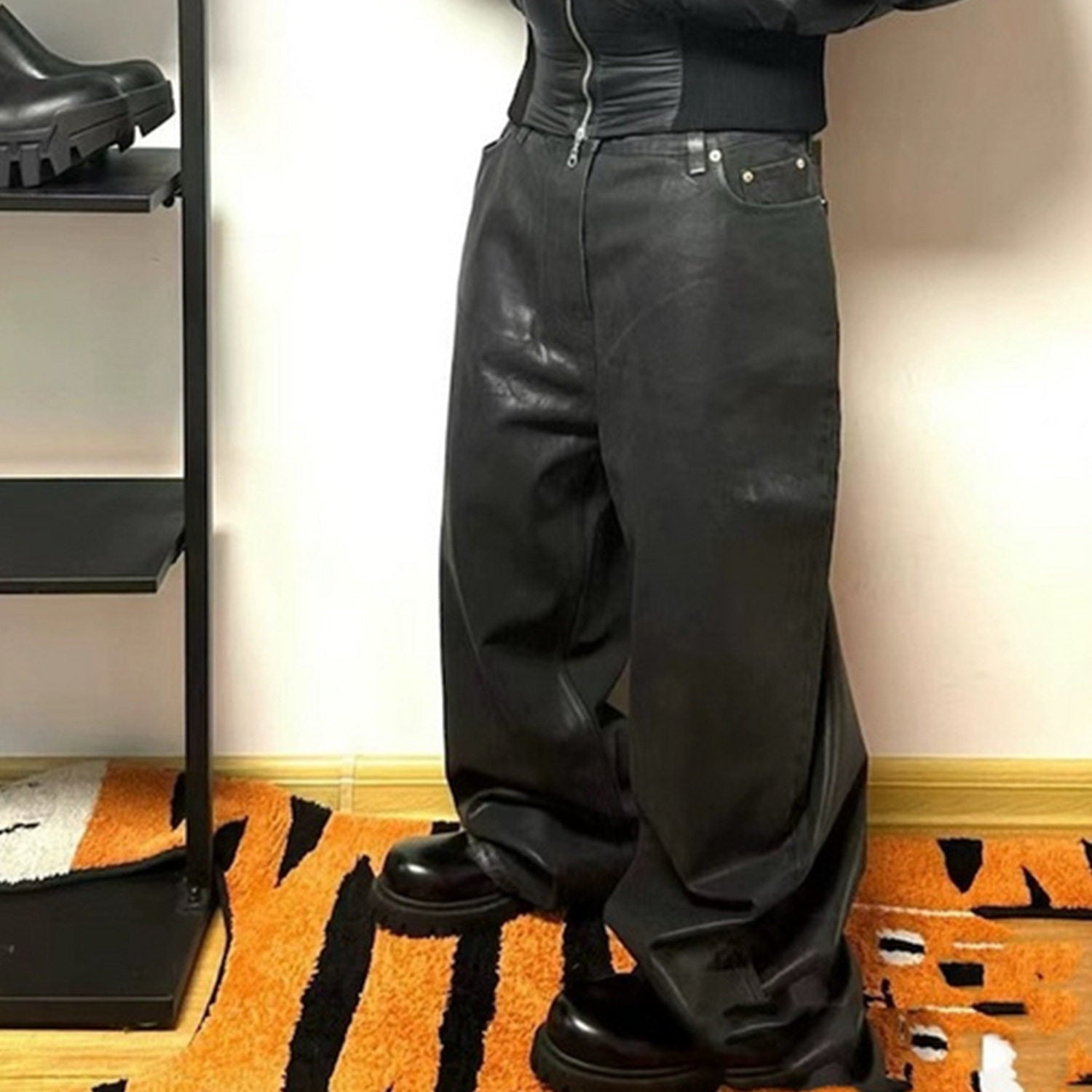 Black coated denim jeans on the body, wide relaxed leg breaking long over chunky black boots indoors