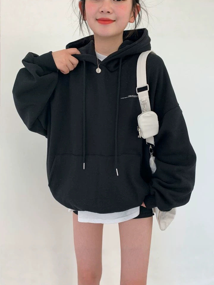 Black oversized hooded sweatshirt with drawstrings and a front pouch pocket, worn with a white shoulder bag