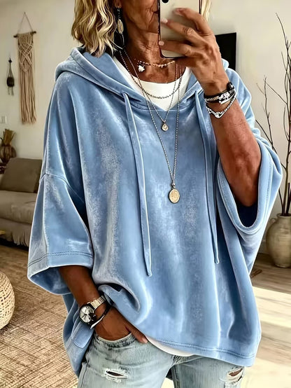 Loose womens hooded top with a drawstring hood shown on a model indoors