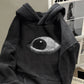 Close up of the oversized eye graphic on the chest of the washed black hoodie