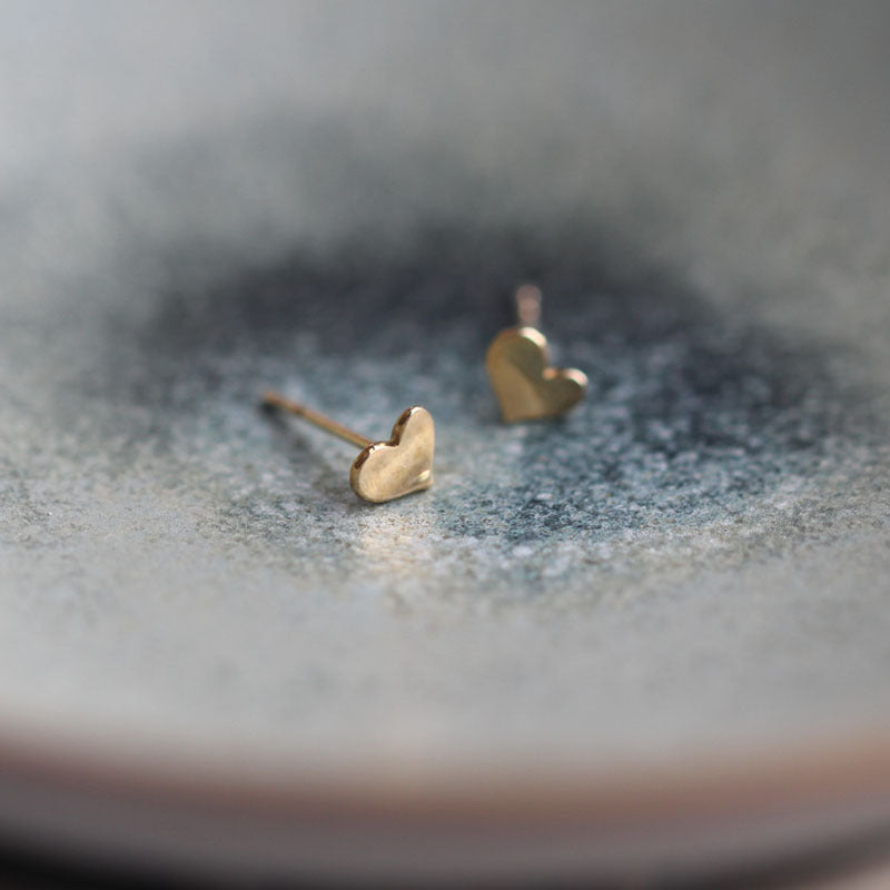 Side profile of the gold-tone heart earring showing the curved edge and post